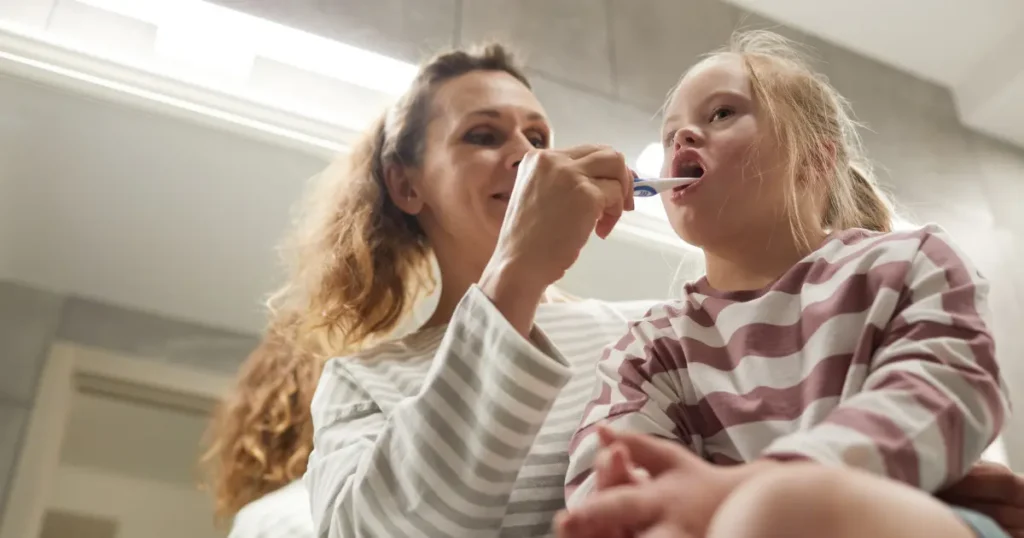 Special Needs Patient Having Teeth Brushed By Caregiver